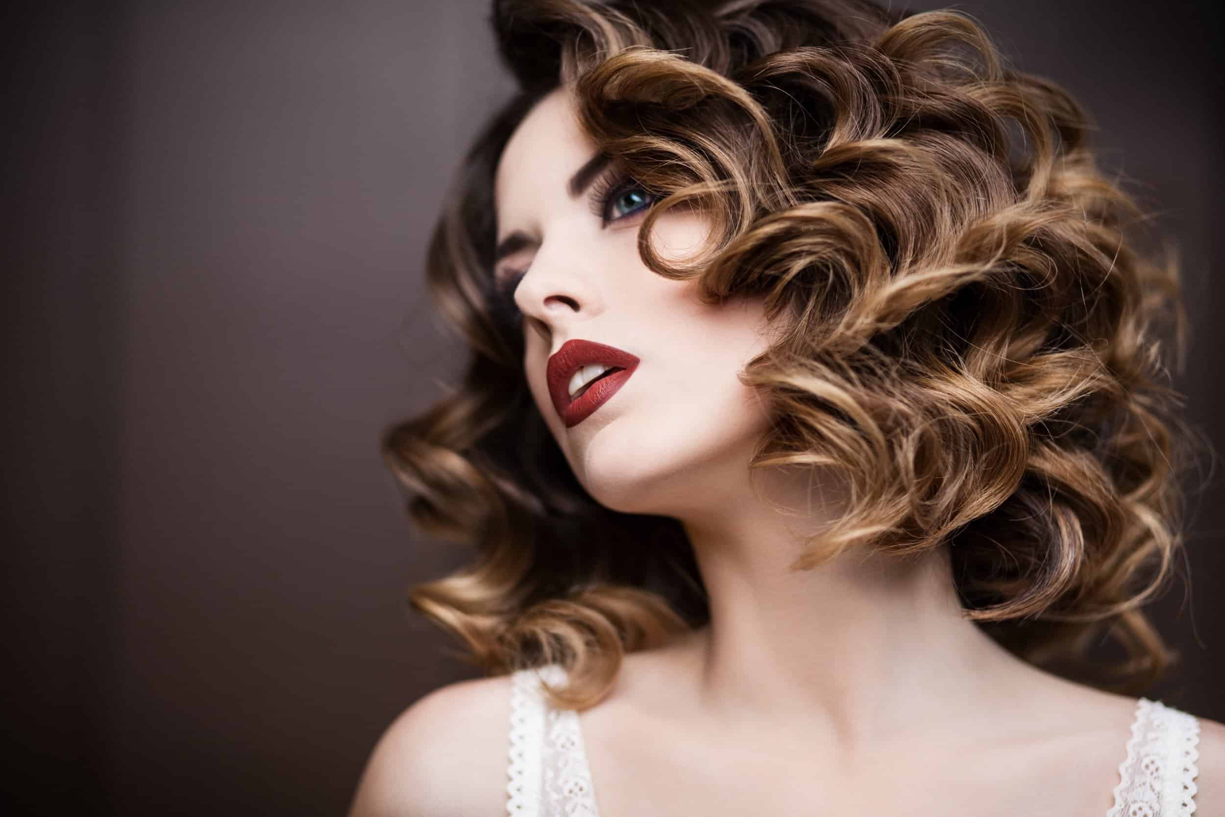 Model with voluminous brunette curls and classic red lipstick